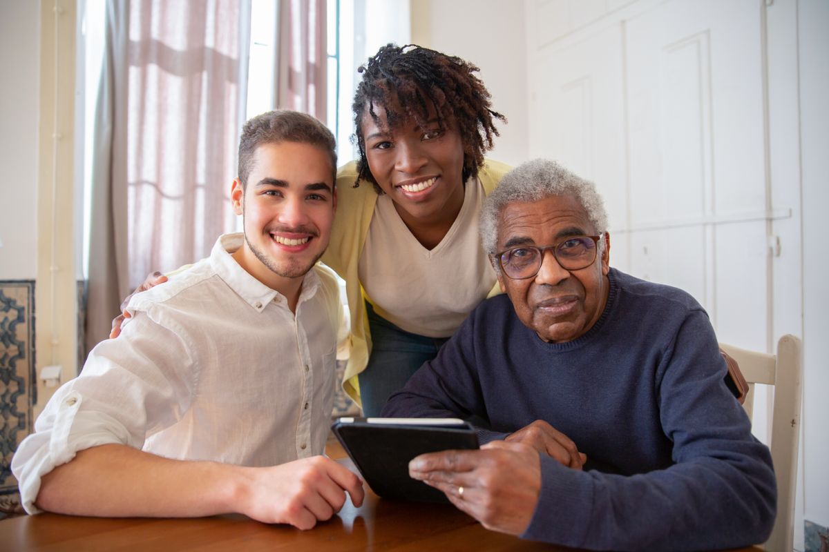 A support worker and two adults smiling together at a table at home